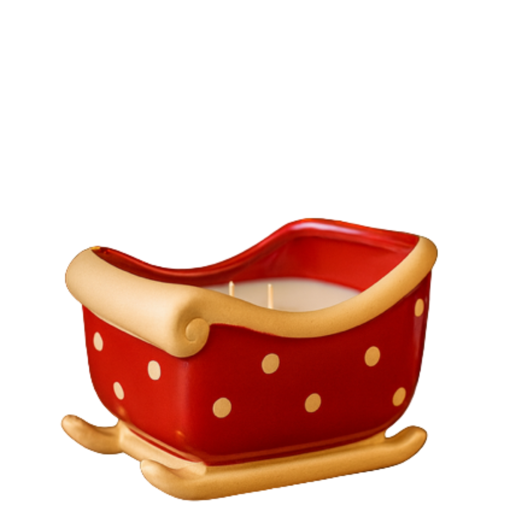 The Sleigh Candle features a red holder with gold trim and polka dots, cradling a white ceramic two-wick candle—ideal for festive Christmas decor.