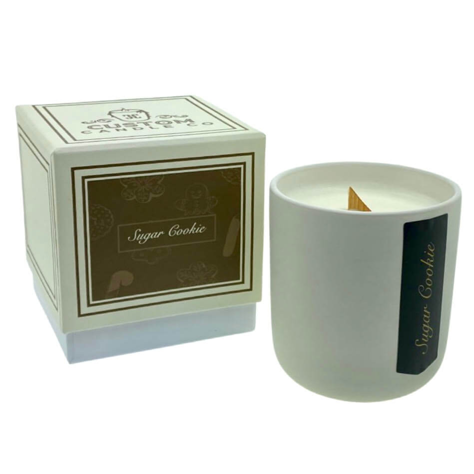 The Holiday Scented Boxed Candle – Sugar Cookie Scent features white soy wax in a matching white container and box, filling your space with the warm, sweet aroma of sugar cookies—perfect for a festive and cozy atmosphere.