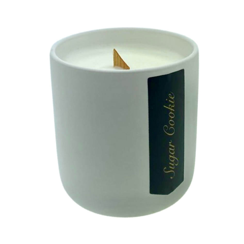 The Holiday Scented Boxed Candle – Sugar Cookie Scent features white soy wax in a ceramic container with a wooden wick and “Sugar Cookie” label, filling your space with the warm fragrance of freshly baked sugar cookies.
