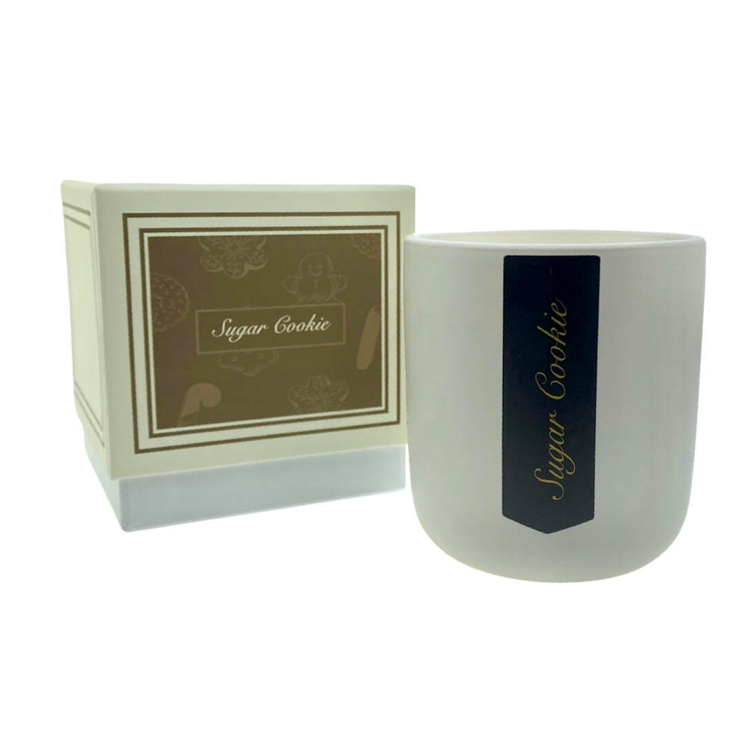 The Holiday Scented Boxed Candle – Sugar Cookie Scent is a white soy wax candle in frosted glass labeled "Sugar Cookie," featuring a rich cookie fragrance and paired with a matching brown and white holiday box.