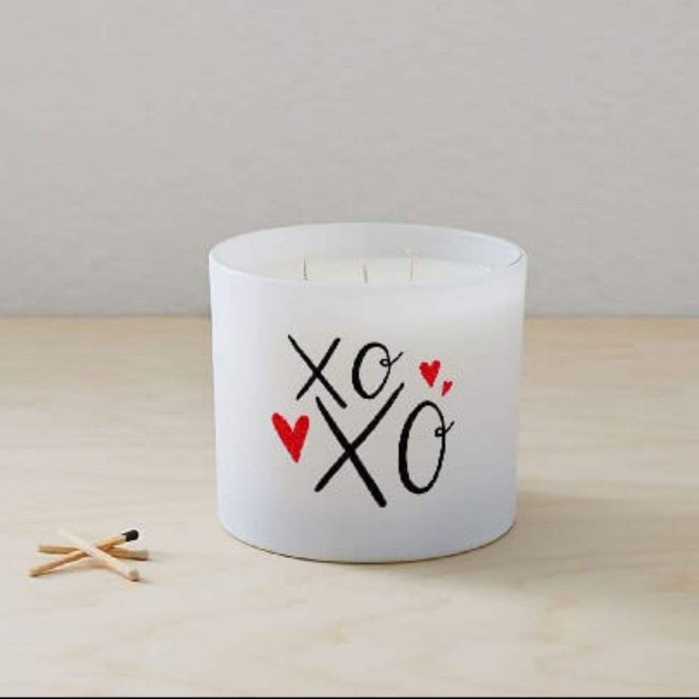 The XOXO Colored Quote Candle comes in a frosted tumbler jar with "xo xo" and two red hearts on the glass, hand-poured for charm and warmth—perfect for any space.