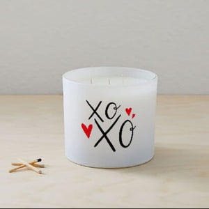 The XOXO Colored Quote Candle comes in a frosted tumbler jar with "xo xo" and two red hearts on the glass, hand-poured for charm and warmth—perfect for any space.