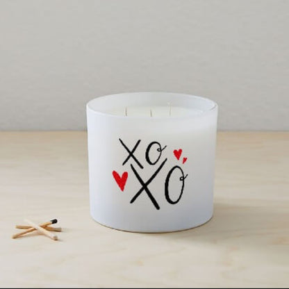The XOXO Colored Quote Candle comes in a frosted tumbler jar with "xo xo" and two red hearts on the glass, hand-poured for charm and warmth—perfect for any space.